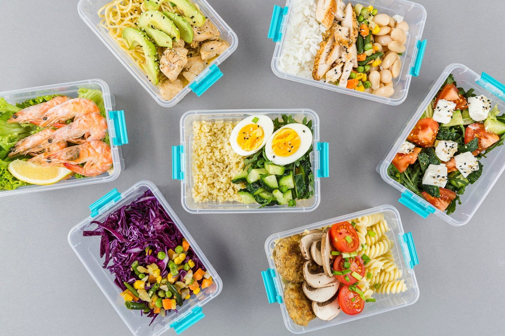 Marmitas de comida congelada saudável organizadas em potes transparentes com tampa azul, prontas para o freezer