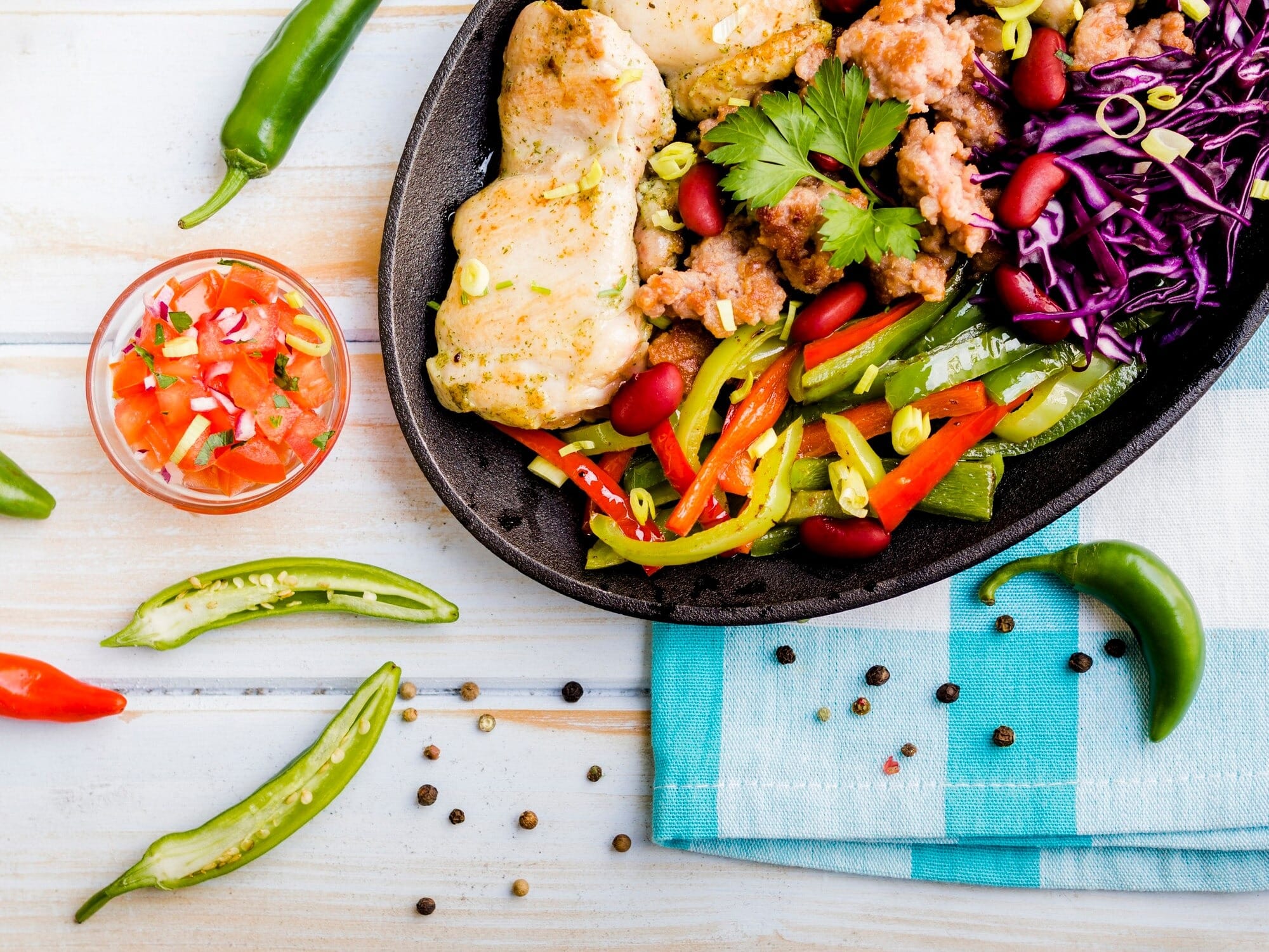 Receitas low carb com frango grelhado, legumes coloridos e salada em frigideira sobre mesa rústica