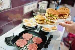 Alt text: "Hambúrgueres artesanais sendo preparados em cozinha — como lotar hamburgueria com produção caprichada e apresentação irresistível