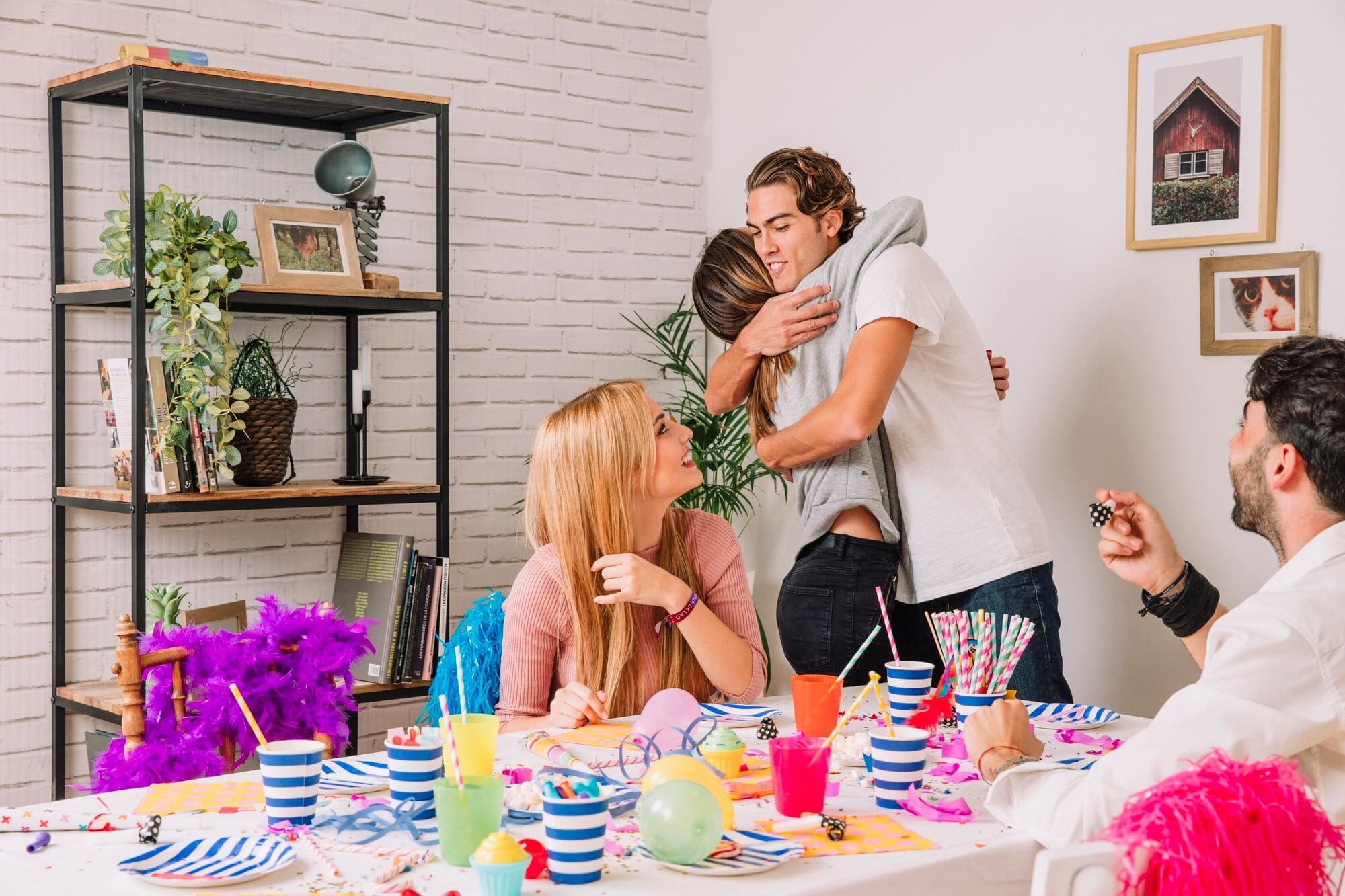 Grupo de amigos celebrando festas temáticas em casa com mesa decorada, copos coloridos, balões e enfeites vibrantes