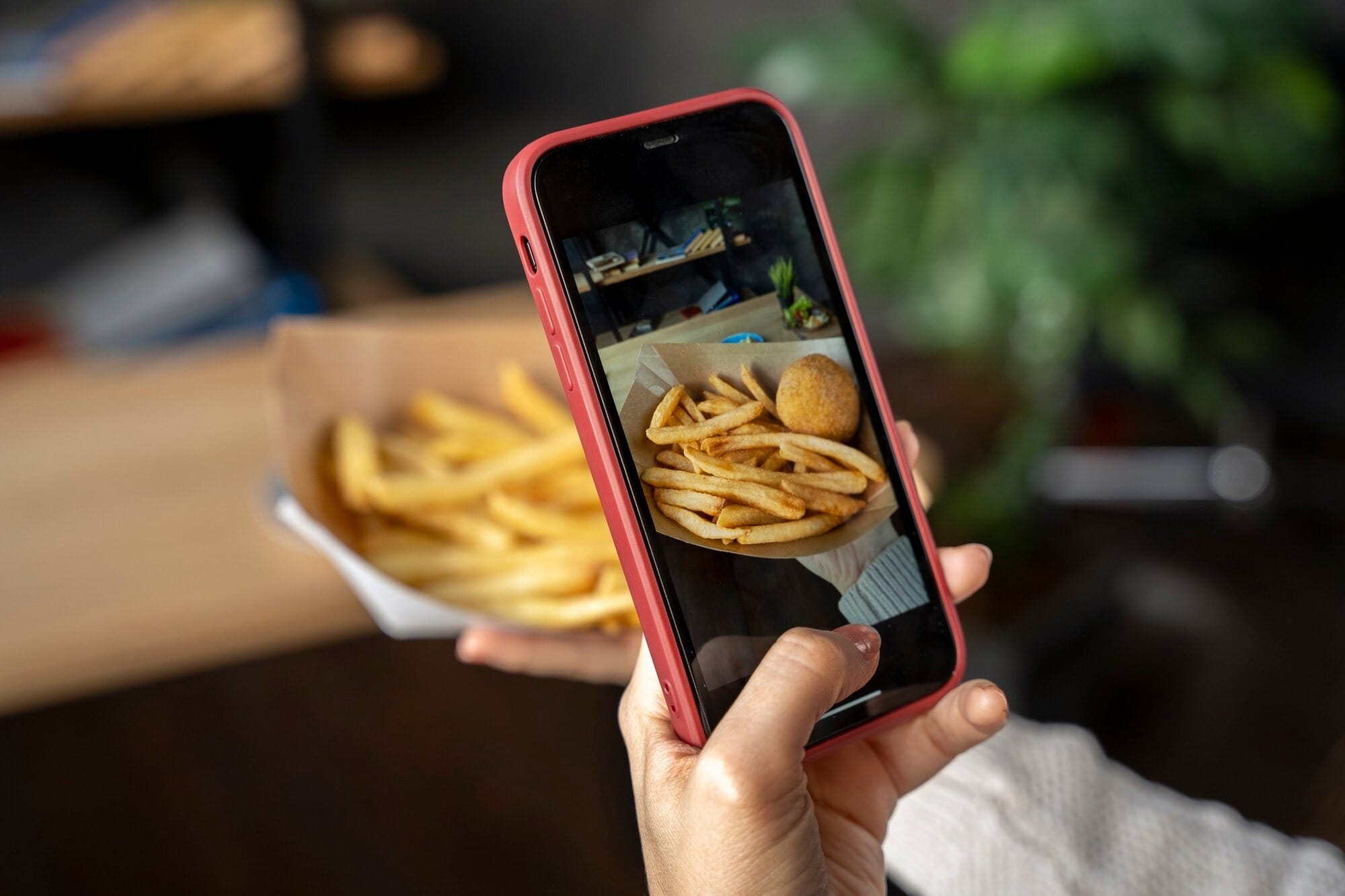 Pessoa fotografando com celular batata frita e salgado de delivery para criar conteúdo de anúncio de tráfego pago para delivery